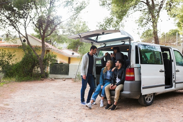 Friends sitting on car trunk