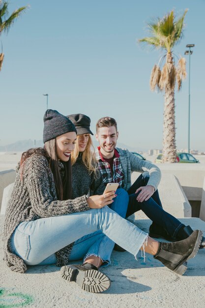 Friends sitting on concrete in front of palm tree