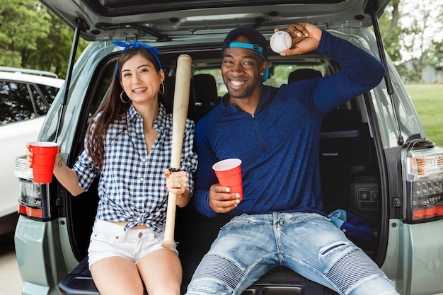 テールゲートパーティーで車のトランクに座って飲んでいる友達