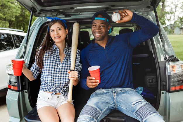 Friends sitting and drinking in the car boot at a tailgate party