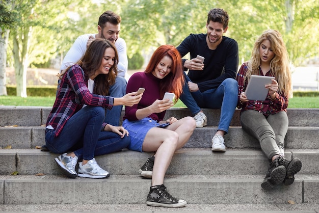 Friends sitting on a few steps with smartphones and tablets