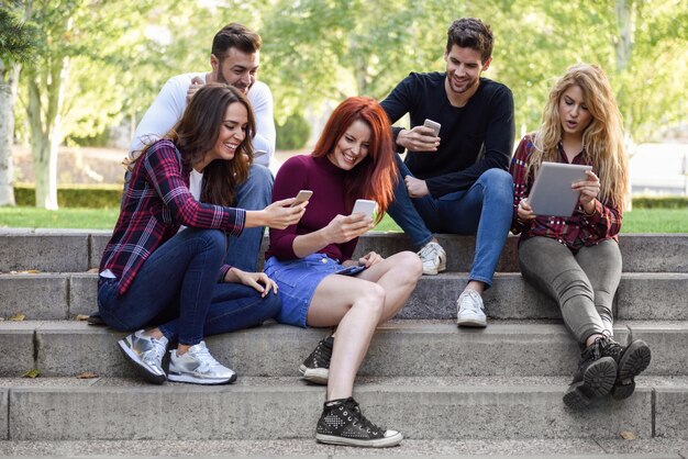 Friends sitting on a few steps with smartphones and tablets