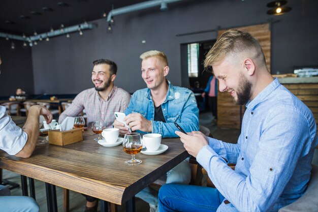 Friends sitting in the restaurant using mobile phone