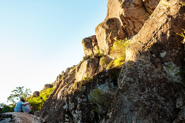 Free photo friends sitting on rock in canyon, embracing