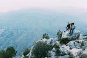 Free photo friends sitting on rock in nature