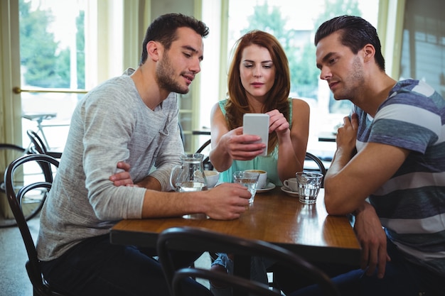 Friends sitting at table and using mobile phone