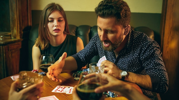 Foto gratuita amici che si siedono al tavolo di legno. amici che si divertono mentre giocano a gioco da tavolo.