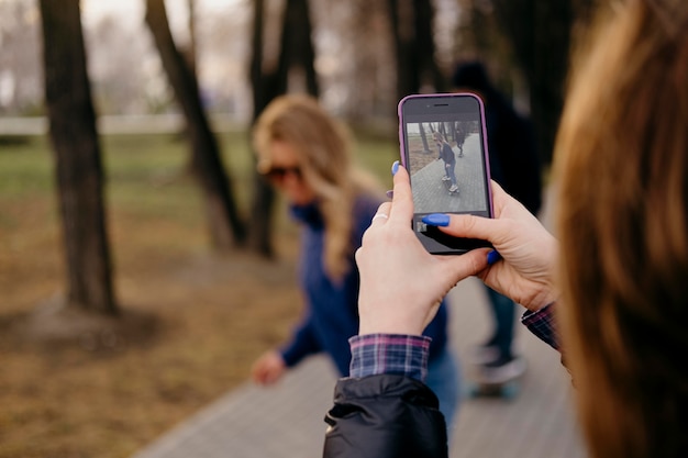 Друзья катаются на скейтборде в парке, пока женщина фотографирует