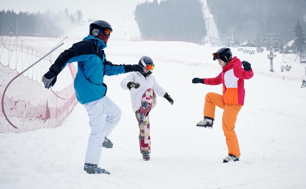 Друзья-лыжники веселятся на горнолыжном курорте в горах зимой, катаясь на лыжах и сноуборде