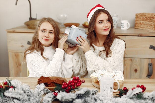 友達は家で時間を過ごしました。二人の女の子がお茶を飲みます。サンタの帽子をかぶった女性。