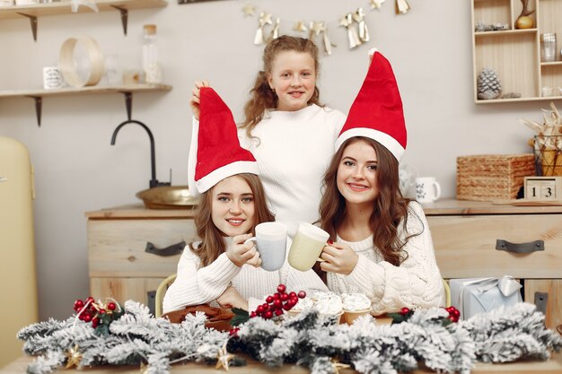 Friends spent time at home. Two girls drink tea. Woman in a santa's hat.