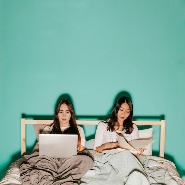 Friends studying in bed