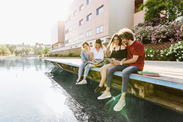 Friends studying near building with lake