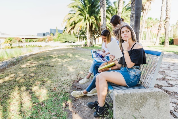 Friends studying sitting on bench in park 