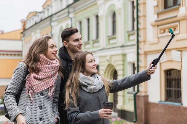 Friends taking selfie with stick on street