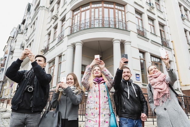 Friends taking shots with gadgets on street