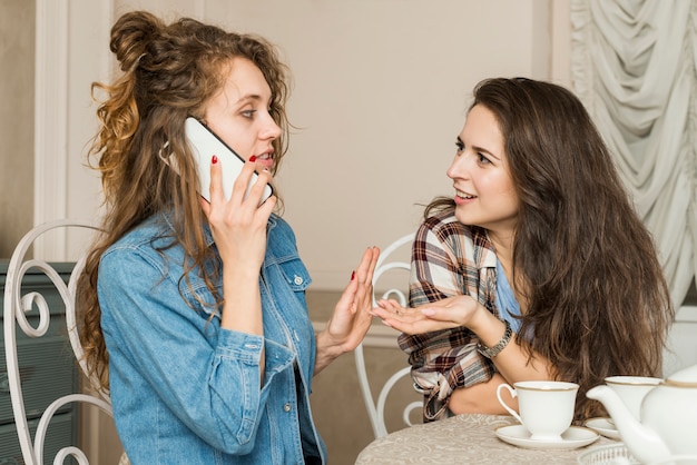 Бесплатное фото Друзья разговаривают по телефону за чашкой чая