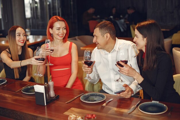 Friends talking and having fun at dinner party. Elegantly dressed group of people having a dinner.