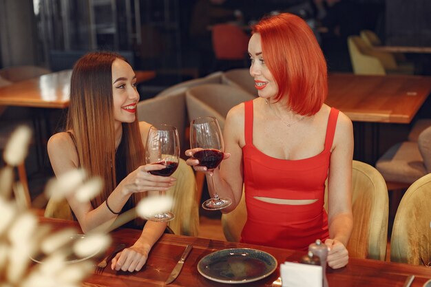 Friends talking and having fun at dinner party. Elegantly dressed women of people having a dinner.