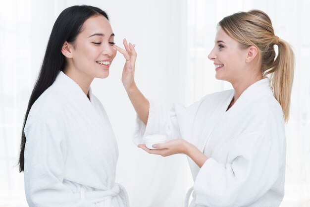 Friends using beauty cream in a spa