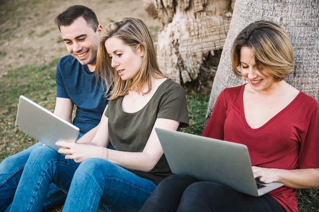 Friends using digital devices in park