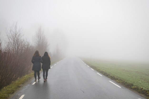 Friends walking along a road leading to the fog