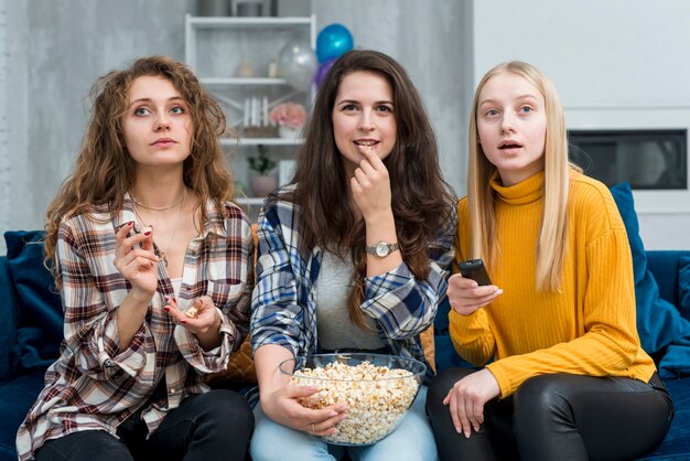 Friends watching a film while eating popcorn