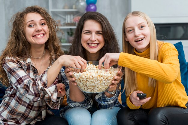 Friends watching a film while eating popcorn