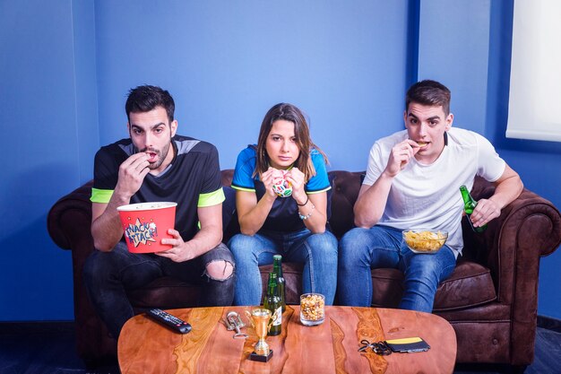 Friends watching football with popcorn