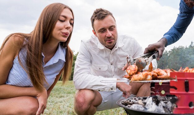 Friends watching the meat getting roasted on barbecue