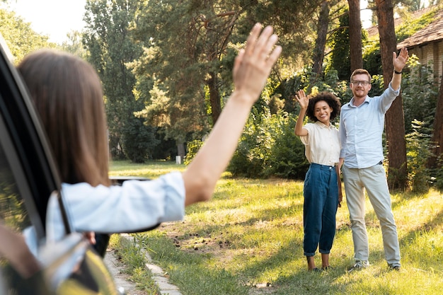 Friends waving at each other outdoors from the car