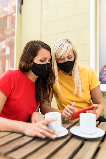 Amici che indossano maschere e si godono un caffè insieme