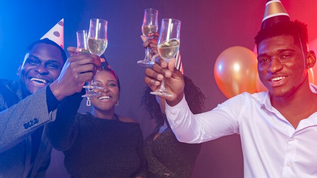 Friends wearing party hats and toasting with champagne