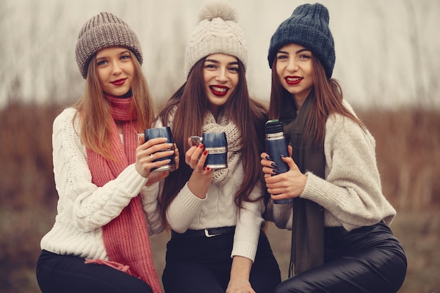 Friends in a winter park. Girls in a knited hats. Women with thermos and tea.