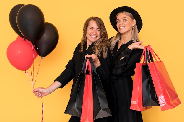 Friends with black and red bags with balloons