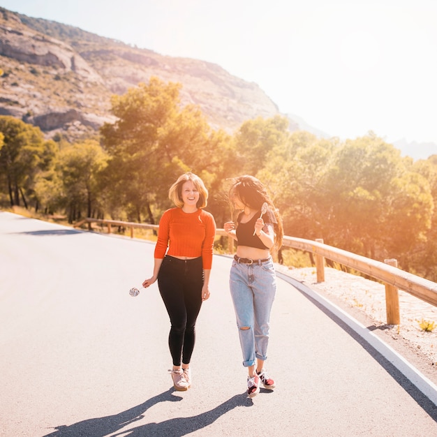 Free photo friends with lollipops walking countryside road