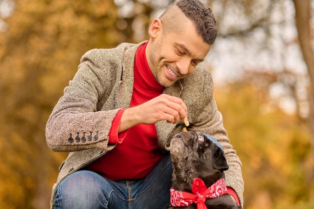 Free photo friends. a young man with his pet in the autumn park