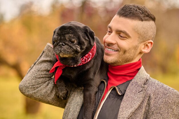 友情。公園で彼の犬と幸せな笑顔の男