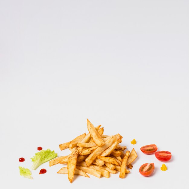 Fries with tomatoes on white table