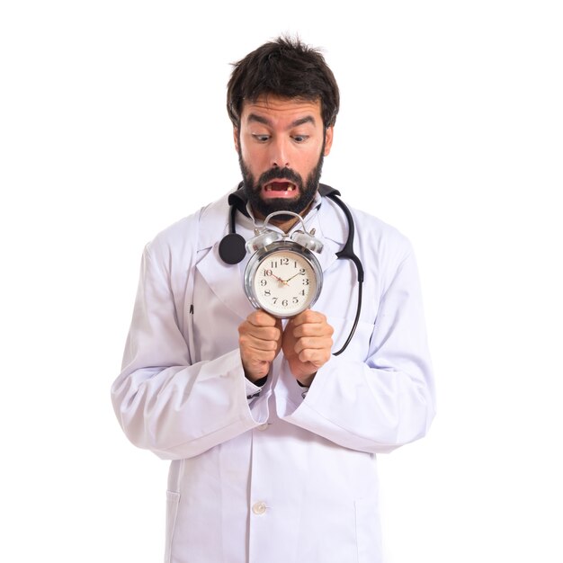 Frightened doctor holding a clock