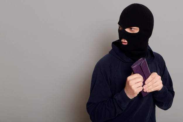 Frightened guy thief dressed in a black hoodie