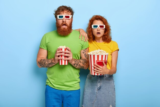 Frightened red haired woman and man being deeply impressed by film