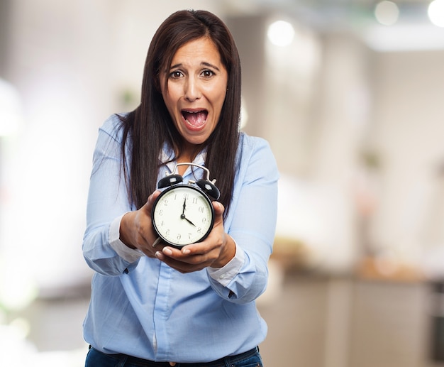 Free photo frightened woman with clock in hands