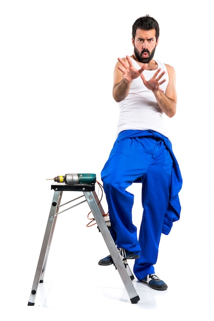 Free photo frightened young electrical technician with a drill