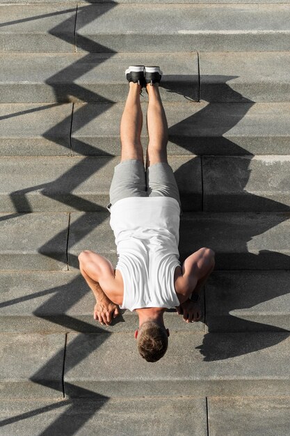 From above athletic man doing push ups on stairs
