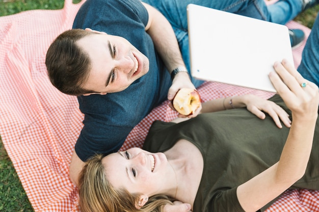 From above couple using tablet on picnic