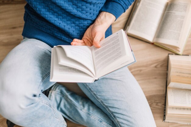 From above man reading book on floor