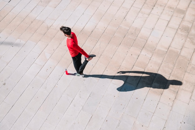 Dall'alto uomo che riscalda i muscoli delle gambe