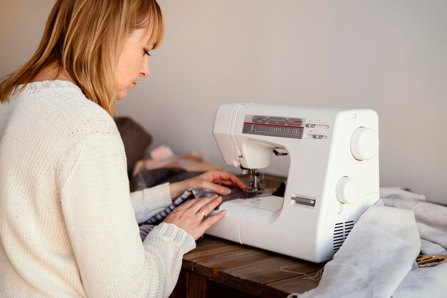 From behind shot woman using sewing machine