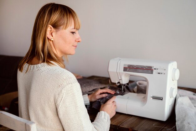from behind shot woman using sewing machine